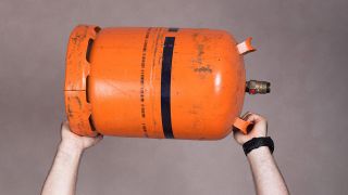 Zwei Hände halten eine orangene Gasflasche in die Luft (Quelle: Colourbox)