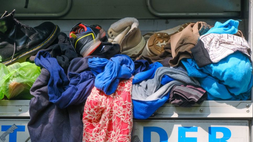 Altkleider auf dem Altkleidercontainer (Quelle: IMAGO / Michael Gstettenbauer)