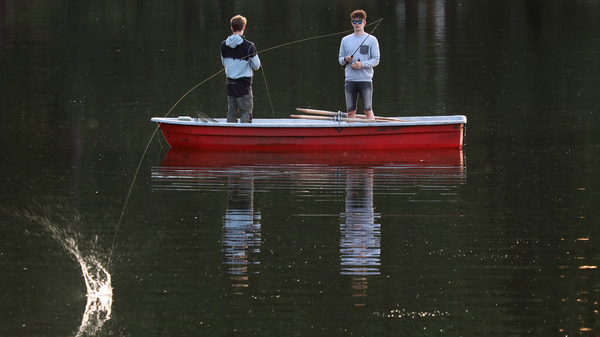 Archivbild: Jugendliche in einem Boot angeln am Abend in einem See. (Quelle: dpa/Sorge)